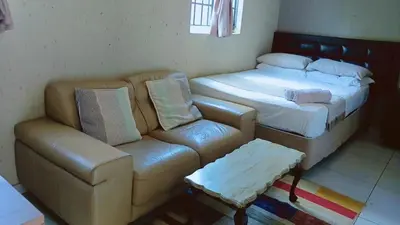 a living room with a couch and a couch and a bed at Eleven on Coulbrough in Midrand
