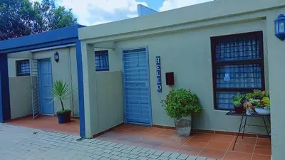 a building with blue doors and plants on a patio at Eleven on Coulbrough in Midrand