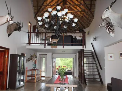 a living room with a chandelier and a table at Koro Lodge in Modimolle