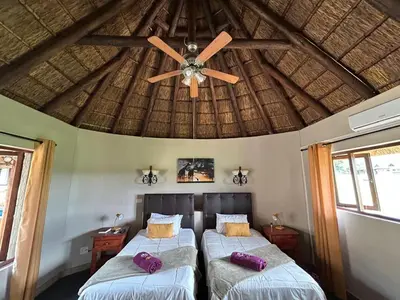 two beds in a room with a ceiling fan at Koro Lodge in Modimolle