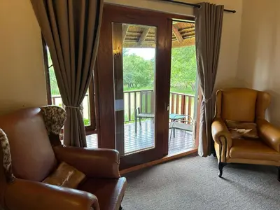 a living room with a chair and a sliding glass door at Koro Lodge in Modimolle