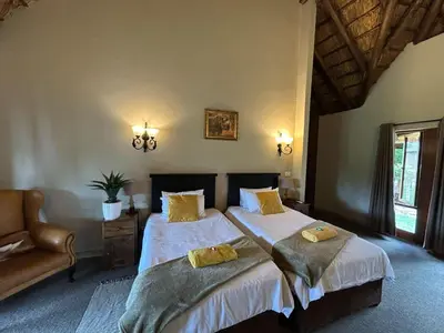 a bedroom with two beds and a chair in it at Koro Lodge in Modimolle
