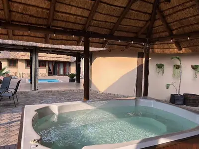 a jacuzzi tub sitting under a wooden roof at Koro Lodge in Modimolle