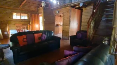 a living room with two leather couches and a staircase at Nomads Rest in Sterkspruit
