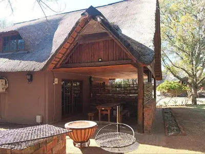 a house with a thatched roof with a picnic table at Rondevue Game Lodge in Warmbaths