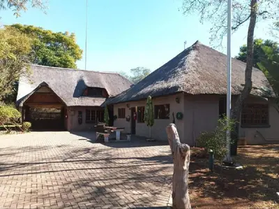 a building with a thatched roof with a bench in front at Rondevue Game Lodge in Warmbaths