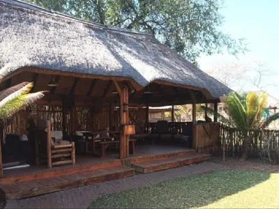 a pavilion with a thatched roof with chairs and tables at Rondevue Game Lodge in Warmbaths