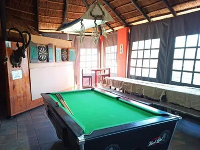 a room with a pool table in a room with windows at Rondevue Game Lodge in Warmbaths