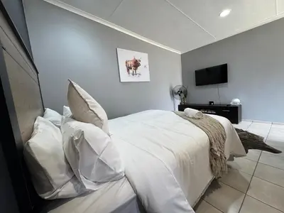 a bedroom with a bed with white sheets and pillows at Be Still Haven in Polokwane
