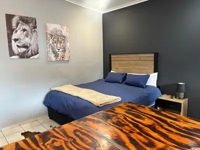 a bedroom with two beds and a tiger painting on the wall at Be Still Haven in Polokwane