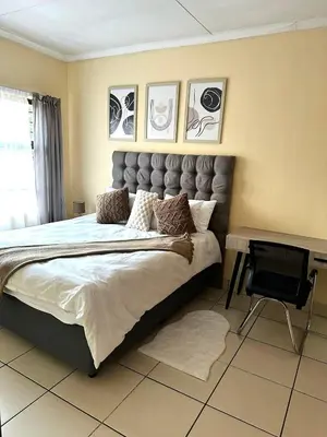 a bedroom with a large bed and a chair at Elephant Springs in Polokwane