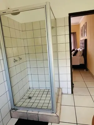a shower with a glass door in a bathroom at Elephant Springs in Polokwane