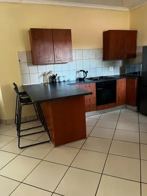 a kitchen with wooden cabinets and a black counter top at Elephant Springs in Polokwane