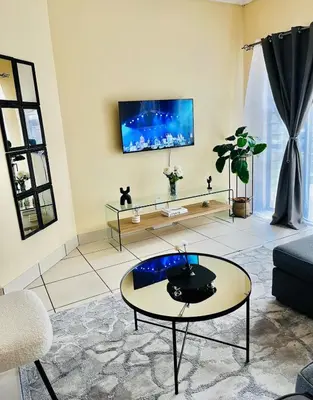 a living room with a table and a tv on the wall at Elephant Springs in Polokwane