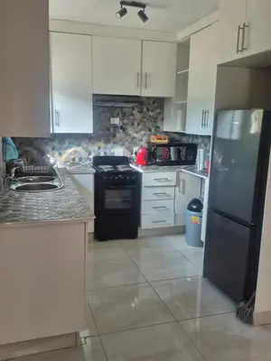a kitchen with white cabinets and a black refrigerator at Hazyview Hideaway in Hazyview