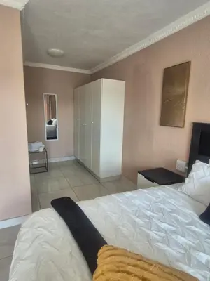 a bedroom with a large white bed and a bathroom at Hazyview Hideaway in Hazyview
