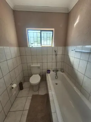 a bathroom with a toilet and a tub and a window at Hazyview Hideaway in Hazyview