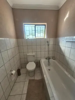 a bathroom with a toilet and a tub and a window at Hazyview Hideaway in Hazyview
