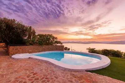 a swimming pool with a sunset in the background at Enso Botanico in Hartbeespoort