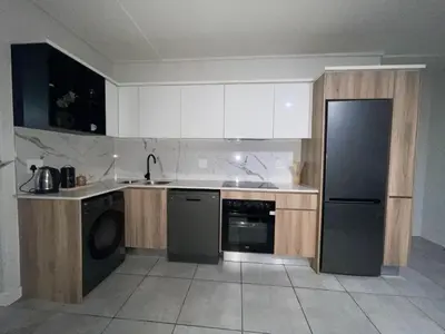 a kitchen with white cabinets and a black refrigerator at Luxor Sky Waterfall city in Midrand