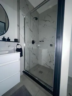 a glass shower in a bathroom with a sink at Luxor Sky Waterfall city in Midrand
