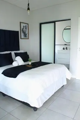 a bedroom with a large white bed with a large window at Luxor Sky Waterfall city in Midrand