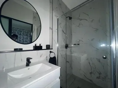 a bathroom with a sink and a mirror and a shower at Luxor Sky Waterfall city in Midrand
