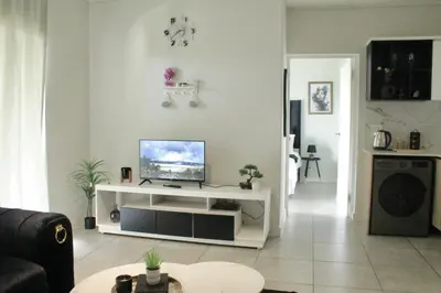 a living room with a television on a white shelf at Luxor Sky Waterfall city in Midrand