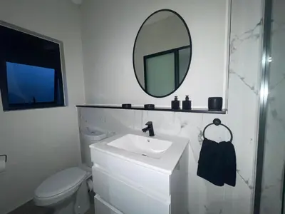 a bathroom with a sink and a mirror over a toilet at Luxor Sky Waterfall city in Midrand