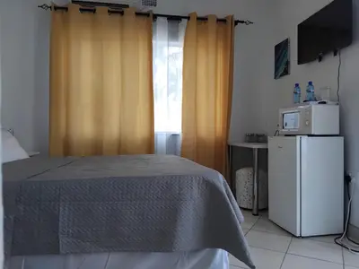 a bedroom with a bed and a window with a microwave at Claremont Secured unit in Pretoria