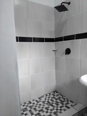 a bathroom with a shower with a black and white tile floor at Claremont Secured unit in Pretoria