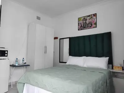 a bedroom with a bed with a green headboard at Claremont Secured unit in Pretoria