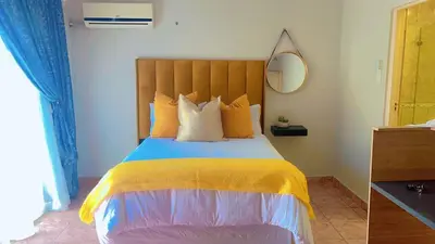 a bedroom with a large bed with a yellow blanket at ekhaya guesthouse in Secunda