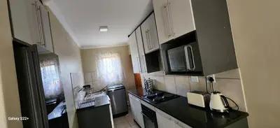 a kitchen with white cabinets and black counter tops at Cloveridge 104 in Benoni