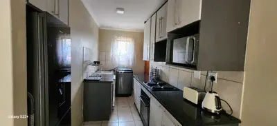 a kitchen with white cabinets and a black counter top at Cloveridge 104 in Benoni