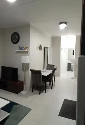 a living room with a table and chairs and a television at Gorgeous Teres place in Midrand