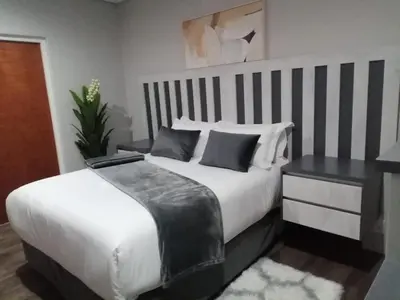 a bedroom with a large white bed and a desk at Diamond and Pearl Holiday Home in Hazyview