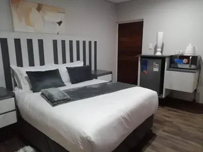 a bedroom with a large white bed with black pillows at Diamond and Pearl Holiday Home in Hazyview