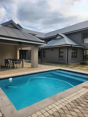 a swimming pool in front of a house at Diamond and Pearl Holiday Home in Hazyview
