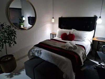 a bedroom with a bed with two red pillows on it at Indulge luxury overnight accommodation in Middelburg