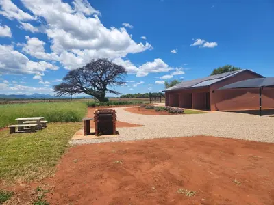 a building with a tree in the middle of a field at Zondereinde Accommodation in Wag ʼn Bietjie Draai