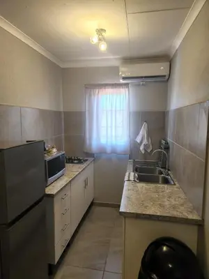a small kitchen with a sink and a microwave at Zondereinde Accommodation in Wag ʼn Bietjie Draai