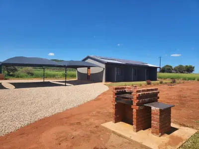 a building with a black umbrella and a brick oven at Zondereinde Accommodation in Wag ʼn Bietjie Draai