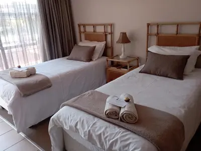 two beds in a hotel room with towels on them at Bloemhoek Guest House in Centurion