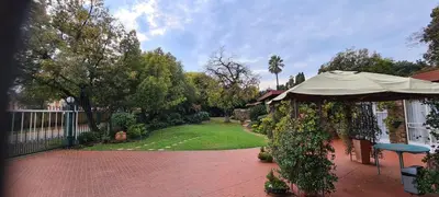 a patio with an umbrella and a yard with a fence at Bloemhoek Guest House in Centurion
