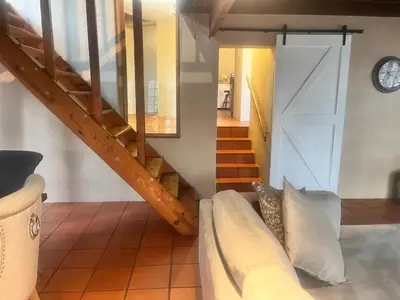 a living room with a couch and a staircase at Executive loft at Brooklyn in Pretoria