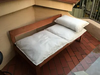 a bench with two white pillows on a balcony at Executive loft at Brooklyn in Pretoria