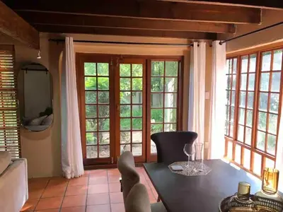 a dining room with a table and some windows at Executive loft at Brooklyn in Pretoria