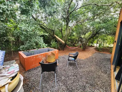 two chairs and a table in a yard with trees at Hartbeest Bush Stay #5 in Hartbeespoort