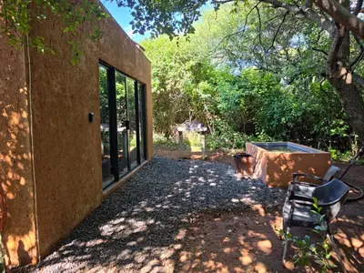 a building with a large window next to a tree at Hartbeest Bush Stay #5 in Hartbeespoort